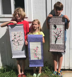 Three students with their sumi-e paintings on scrolls